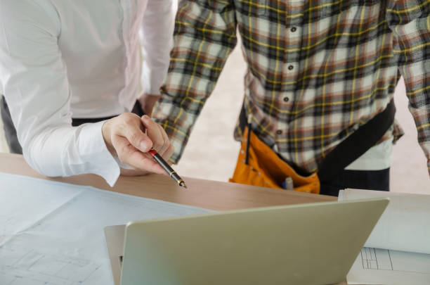 istock project manager pointing with pen on laptop computer with construction worker team and blueprint on desk during discussing planing for new project at construction site, contractor, engineering concept 1206443170