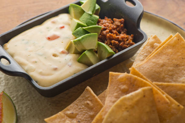 Queso cheese dip. Traditional classic Tex-Mex/Mexican restaurant appetizer favorite. Queso dip melted cheeses mixed with spices and hot sauce. Served with homemade tortilla chips avocado & meat