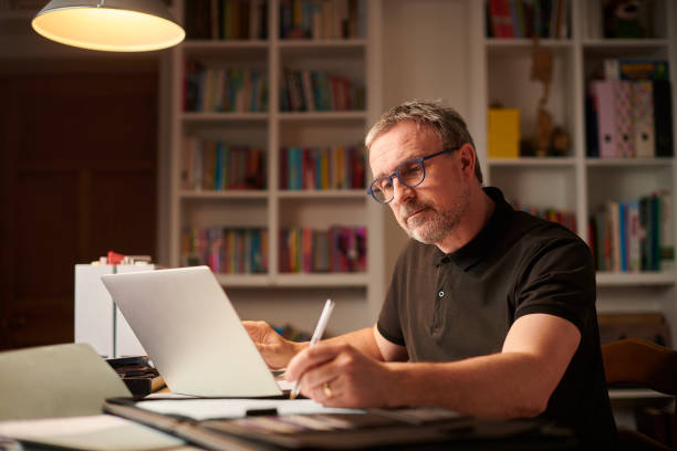 home office working late mature man working from home or sorting the home finances middle age adult studying stock pictures, royalty-free photos & images