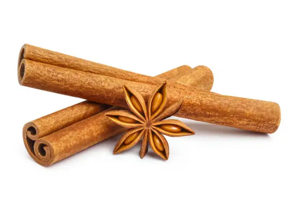 Photo of Delicious cinnamon sticks and star anise on white