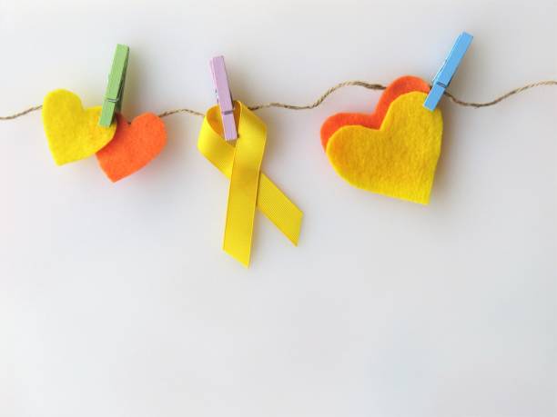 Yellow ribbon, hearts, pinned to clothesline--Awareness month: suicide; endometriosis; military; firefighters Yellow ribbon, hearts, pinned to clothesline-Awareness month: suicide; endometriosis; military; firefighters.White background. Copy space. christine kohler stock pictures, royalty-free photos & images