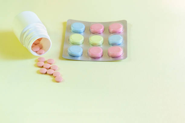istock Pink, yellow and blue tablets on a yellow table. Multicolored medicines for the prevention and treatment 1206466964