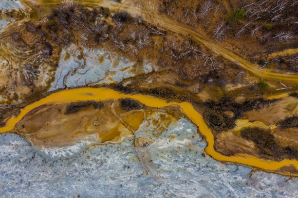 istock Aerial view drone flying forward over polluted river with destroyed ecosystem and copper tailing dump poisoning ground and water air emissions from industry environmental disaster in South Ural 1206469920