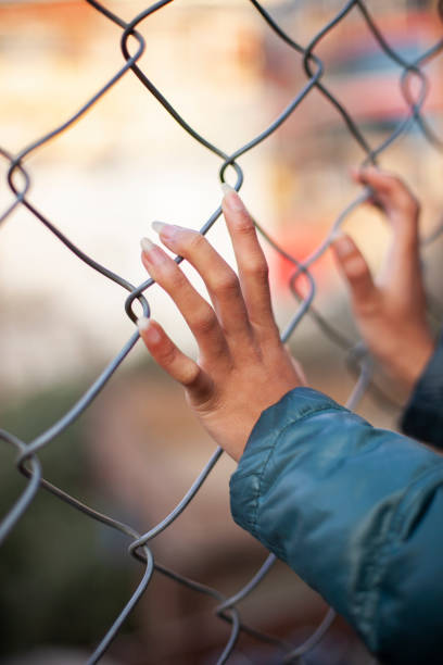 istock Close-up of hands holding chain-link fence. 1206482621