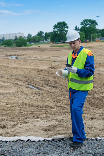 istock a man in a helmet holds a road construction plan and calls for management reporting 1206489589