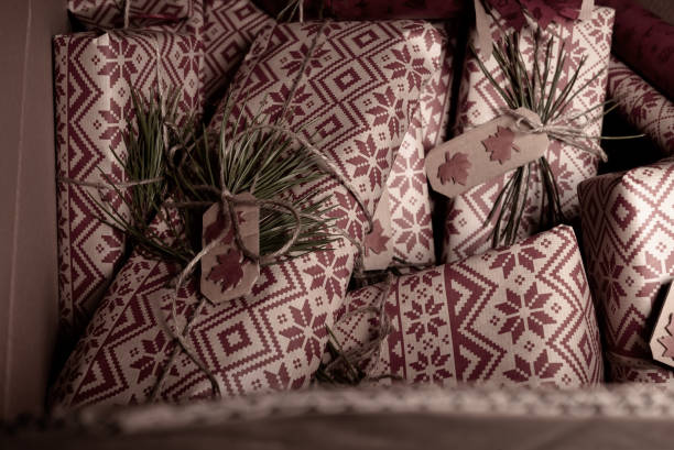 istock Many secret christmas presents piled up in a box with creative handmade decorative rustic diy gift wrapped in red retro wrapping paper with natural vintage twine and spruce twigs as decor, hidden away until Xmas Eve 1206492301