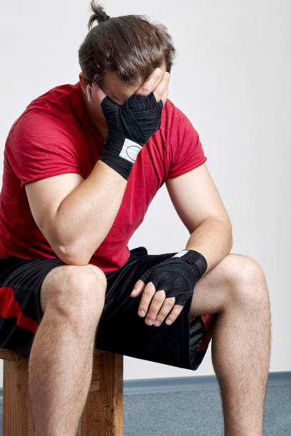 młody kaukaski mężczyzna w odzieży sportowej i bandażach bokserskich siedzi z dłonią. - brzask ranny zdjęcia i obrazy z banku zdjęć