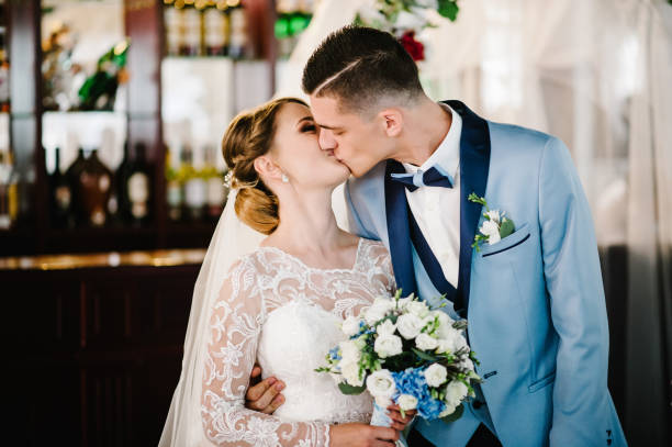 feliz beijo de noiva e noivo após cerimônia de casamento sob o arco decorado com flores e vegetação. alguns recém-casados. - couple love old fashioned traditional culture - fotografias e filmes do acervo