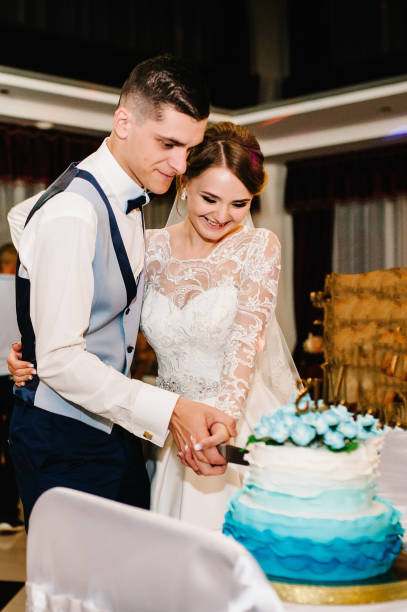 istock Bride and a groom is cutting their rustic wedding cake on wedding banquet. Hands cut the cake with delicate blue flowers. 1206501335