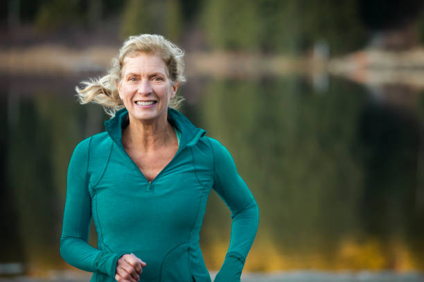 Close up of senior woman running by lake. stock photo
