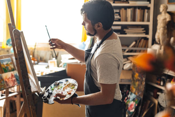 istock Male painter at art studio indoors with palette looking at brush inspired 1206506701