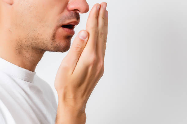 istock Bad breath. Halitosis concept. Young man checking his breath with his hand. 1206507216
