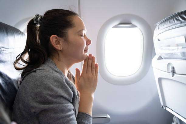 istock Young Woman Praying In Airplane 1206509370