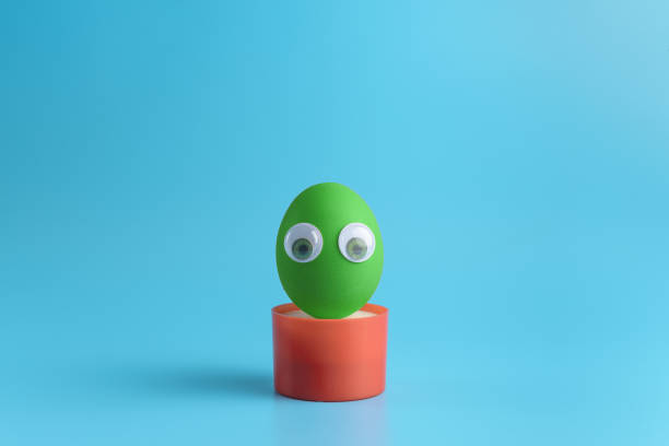 istock One green egg with eyes in a round red box on a blue background. Minimal Happy Easter concept decoration. Copy space for text mockup. 1206520141