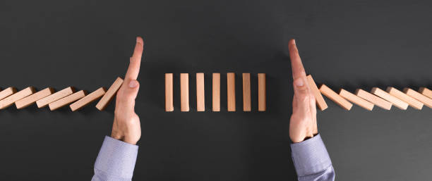 istock businessman protects his investment with two hands from falling dominoes 1206522892