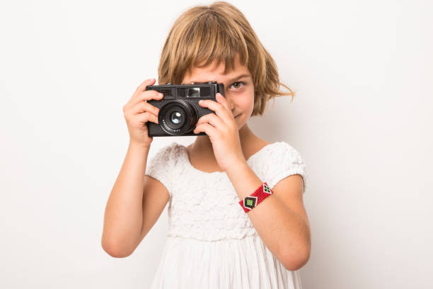 istock little girl playing with a vintage camera and having fun. white background 1206523020