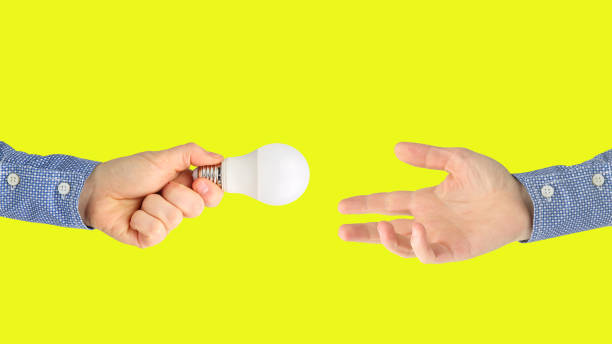 istock two hands with led lamp on bright yellow background 1206530991