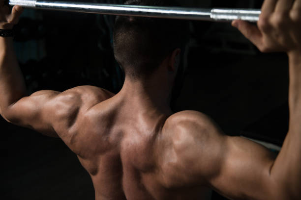 istock Man In The Gym Exercising Shoulder With Barbell 1206531801