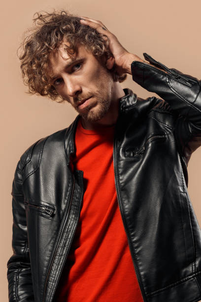istock Freestyle. Man with curly hair in laser jacket standing isolated on bage touching head posing pensive 1206531946