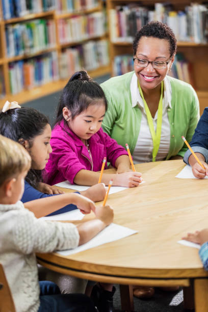 istock Teacher with children sitting at table, writing 1206535598