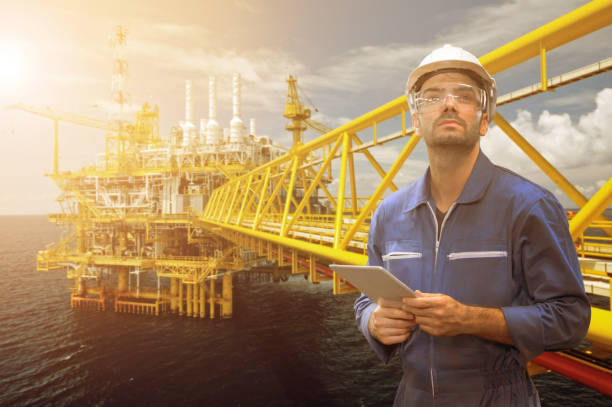 istock man engineer staff worker with tablet in hand and offshore rig background concept. 1206537098