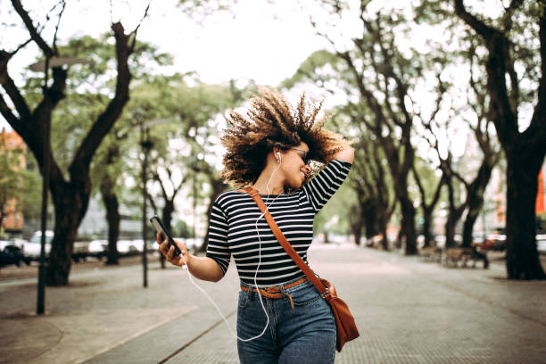 feliz mulher hispânica ouvindo música e dançando na rua - headphones women music dancing - fotografias e filmes do acervo