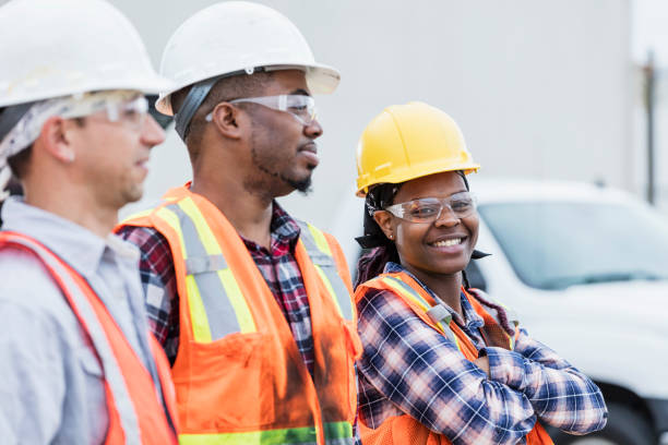 tres trabajadores de la construcción en cascos y chalecos de seguridad - horizontal female with group of males posing looking at camera fotografías e imágenes de stock