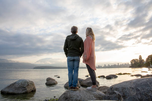 istock Mature couple relax on beach rocks at sunrise 1206540826