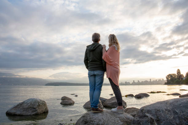 Mature couple relax on beach rocks at sunrise