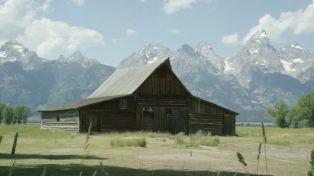 An Old Wooden Cabin/Barn Sits at the Base of the Grand Teton Mountains in Grand Teton National Park in Western Wyoming on a Sunny Day