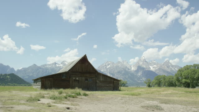 An Old Wooden Cabin/Barn Sits at the Base of the Grand Teton Mountains in Grand Teton National Park in Western Wyoming on a Sunny Day