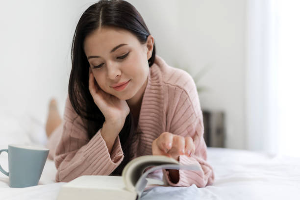 istock Young woman relaxing and reading book on bed at home 1206559093