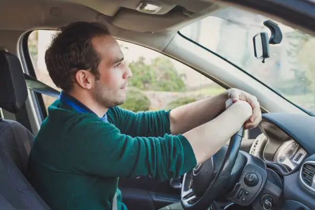 Car driver waiting in a traffic jam on the road. Caucasian man driving.