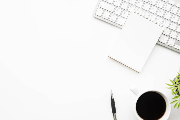 istock White office desk table with blank notebook page with pen, cup of coffee and small plant pot. Top view with copy space, flat lay. 1206563710