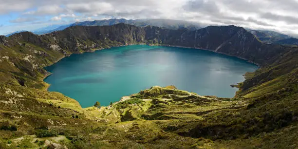 Panorama of the turquoise volcano crater lagoon of Quilotoa along the famous hike called Quilotoa Loop near Quito, Ecuador.