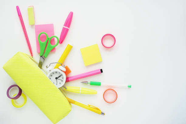 istock Stationery items in bright colors falling from a bright yellow pencil case. Flat layout, top view on a white background. 1206573629