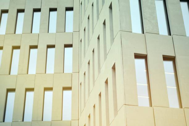 istock Perspective view of geometric angular concrete windows on the facade of a modernist brutalist style building surface with sunlight. 1206578120