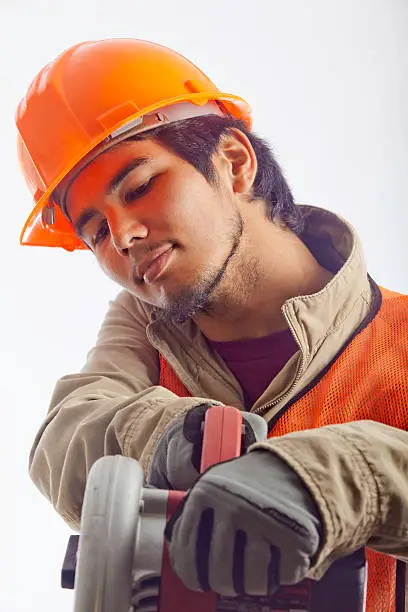 asian hardhat worker with an electric skillsaw