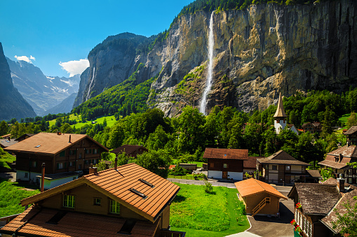 Admirable charming mountain village with high waterfalls and idyllic chalets. Famous travel and touristic place, Lauterbrunnen village with Staubbach waterfall in background, Bernese Oberland, Switzerland, Europe