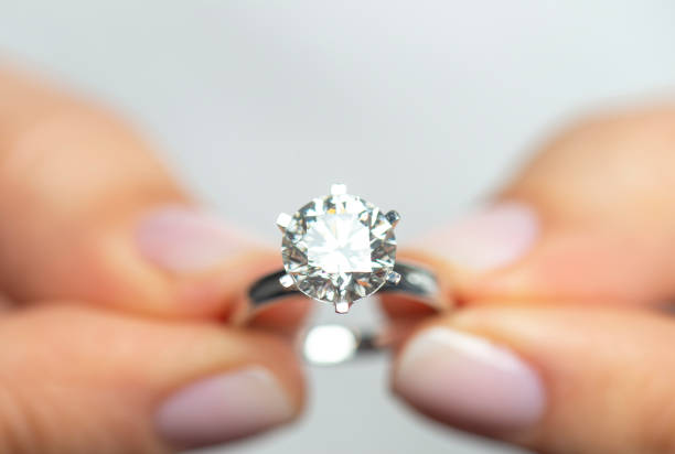 vrouw die een diamanten ring houdt - diamantring stockfoto's en -beelden