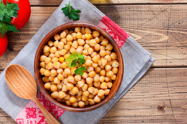 istock Boiled chickpeas in a wooden bowl on a wooden table, top view, horizontal, copy space 1206583128