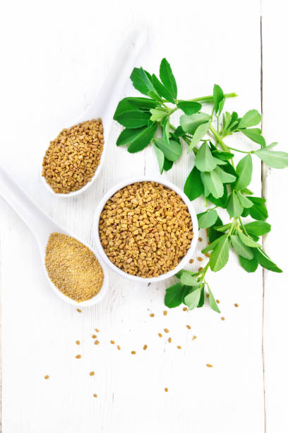 istock Fenugreek in bowl and two spoons with leaves on light board top 1206584176