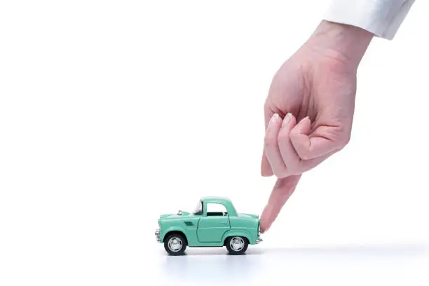 Photo of Woman’s hand assists the toy car to drive