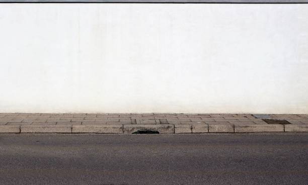 istock White painted wall, concrete sidewalk and an asphalt road. 1206587889