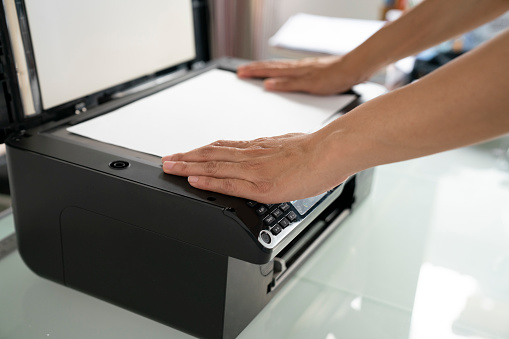 woman hands putting a sheet of paper into a copying device, business in the office time concept