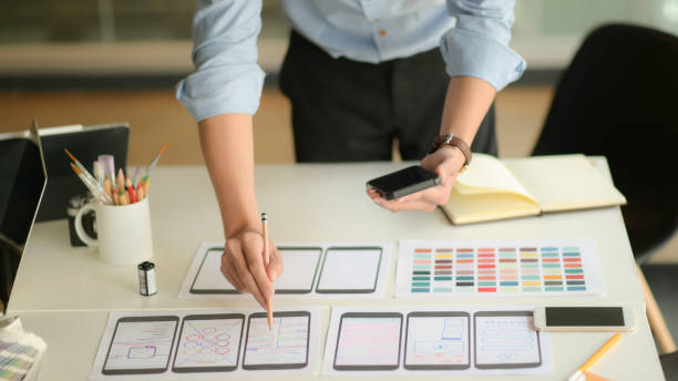 istock Cropped shot of young ux designer working on new application project while using smartphone in modern office room. 1206594759