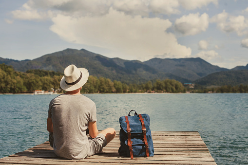 travel, summer holidays, tourist with backpack relaxing on wooden pier, vacation trip