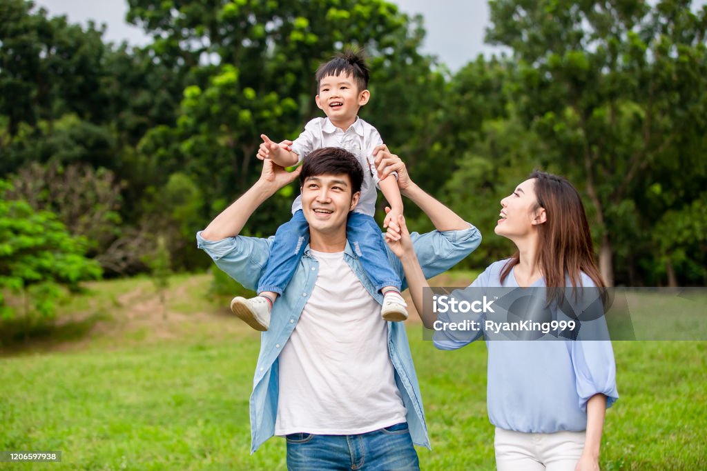 Young parents show the view to kid Young parents show the view to kid when let him sit on father shoulder Family Stock Photo