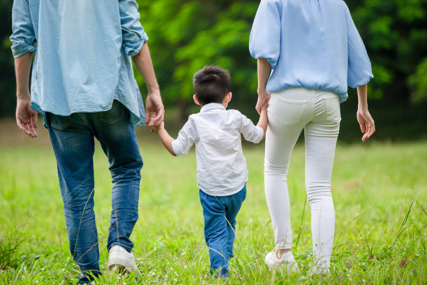young parents walking with kid young parents and kid holding hand and take a walk in the park kids holding hands stock pictures, royalty-free photos & images