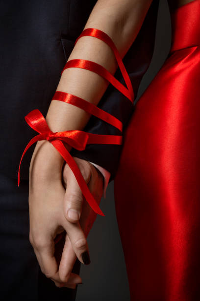para związane ręce, kobieta i mężczyzna broni połączone ze sobą przez czerwoną wstążkę, związek - infidelity sensuality couple men zdjęcia i obrazy z banku zdjęć
